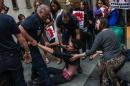 Police officers help a demonstrator to his feet after he fainted during a clash with the police in Paris, France, Wednesday, July 8, 2015. Animal rights activists staged a protest against designer Karl Lagerfeld's fur-only couture show for Fendi on Wednesday. The animal-rights Brigitte Bardot Foundation claimed responsibility for disruption — when an unnamed woman, dressed in a fur coat, ripped it off outside the venue to reveal beneath a shocking bloodied body suit, with breasts visible. Other animal rights activists tried to storm the gate unsuccessfully. (AP Photo/Kamil Zihnioglu)