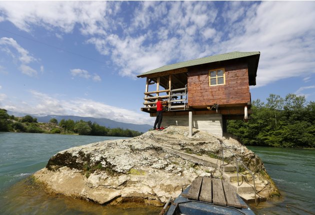 A man enters a house built on a rock on the river Drina near Bajina Basta