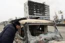 A man looks into a burnt-out car near the Press House building, a local media agency, in the Chechen capital Grozny
