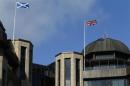 A Scottish Saltire flag and a Union flag of the United Kingdom fly above Standard Life House in Edinburgh, Scotland