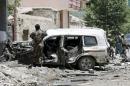 A member of the Afghan security forces investigates next to a destroyed vehicle at the site of a suicide attack in Kabul