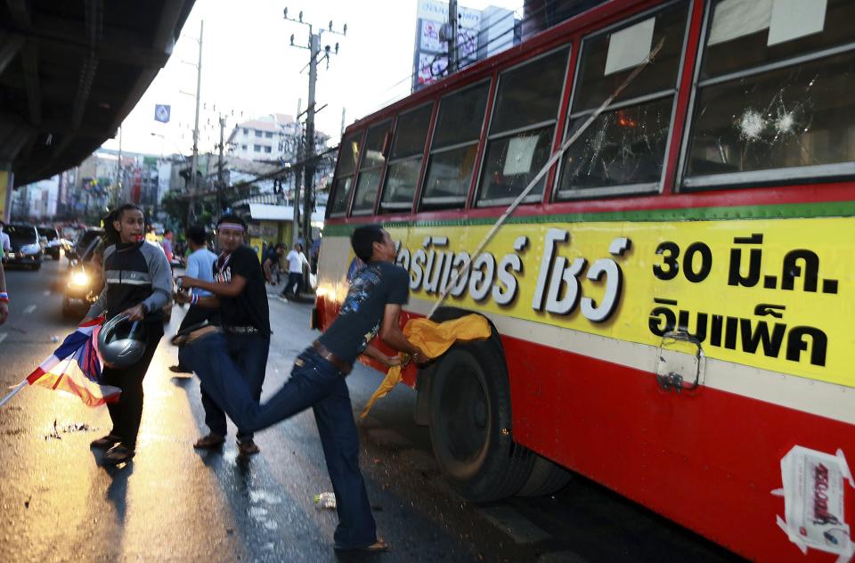 Anti-government protesters attack people they suspected of supporting the current Thai government on the bus in Bangkok,Thailand Saturday, Nov. 30, 2013. A mob of anti-government protesters smashed the windows of a moving Bangkok bus Saturday in the first eruption of violence after a week of tense street protests.(AP Photo/Wason Wanichakorn)