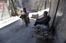 In this picture taken on Monday September 24, 2012, Free Syrian Army fighter sit at one of their positions next to closed shops at the souk in the old city of Aleppo city, Syria. Fires sparked by clashes between government troops and rebels raged through the medieval marketplace of Aleppo on Saturday, destroying hundreds of shops lining the vaulted passageways where foods, fabrics, perfumes and spices have been sold for centuries, activists said. (AP Photo/Hussein Malla)