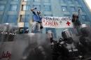 FILE - In this April 7, 2011 file photo, students hold up a sign that reads in Spanish "Impunity Soacha equals false positives" during a protest where police stand guard in Bogota, Colombia. Military jargon identifies a 
