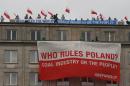 Climate activists with protest banners wave polish flags on the rooftop of the Economy Ministry in Warsaw, Poland Monday, Nov. 18, 2013. They went up the rooftop to protest a coal conference opening to coincide with U.N. talks on preventing global warming, that is also the result of greenhouse gases coming from burning coal. (AP Photo/Czarek Sokolowski)