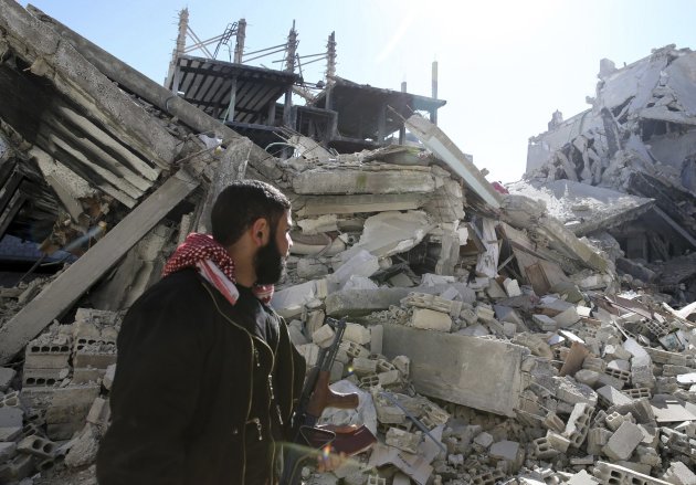 A Free Syrian Army fighter carries his weapon as he walks past damaged buildings in the Arabeen neigbourhood of Damascus, February 12, 2013. REUTERS/Mohammed Abdullah (SYRIA - Tags: POLITICS CIVIL UNREST CONFLICT)