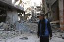 A man stands amid the rubble of damaged buildings at the Palestinian refugee camp of Yarmouk, south of Damascus