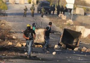 Palestinian protester runs during clashes with the Israeli troops near the Jewish settlement of Beit El, near the West Bank city of Ramallah