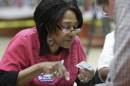 election worker Dorothy Davis checks a voter's ID at a polling place in Little Rock, Ark.