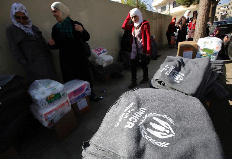 Syrian refugees receive thermal blankets and other humanitarian aid distributed by the United Nations High Commission for Refugees in the Lebanese town of Saadnayel in the Bekaa valley on November 15, 2013