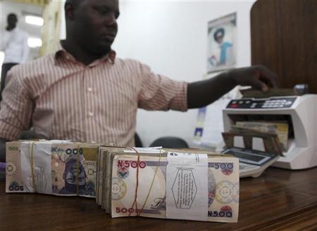 A money dealer counts the Nigerian naira on a machine in his office in the commercial capital of Lagos, January 13, 2009. REUTERS/Akintunde Akinleye