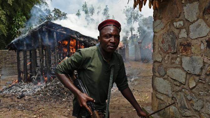 A Burundian soldier runs from a house set on fire by protesters in Butagazwa, on June 5, 2015