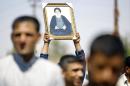 An Iraqi man holds up a portrait of Shiite cleric Grand Ayatollah Ali al-Sistani during a demonstration in the central Shiite Muslim shrine city of Najaf on June 14, 2014
