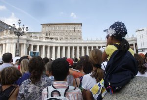 A crowd listens to Pope Francis, small figure seen …