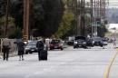Residents are escorted to their home near a Black SUV that was involved in Wednesday's police shootout with suspects, Thursday, Dec. 3, 2015, in San Bernardino, Calif. A heavily armed man and woman dressed for battle opened fire on a holiday banquet for his co-workers Wednesday, killing multiple people and seriously wounding others in a precision assault, authorities said. Hours later, they died in a shootout with police. (AP Photo/Chris Carlson)