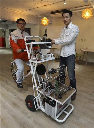 Kamm Kai-yu, a co-founder of boutique design studio Fabraft, displays a bicycle with a 3D printer installed in front, in Taipei