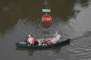 In this aerial photo, people canoe through floodwaters past a stop sign near Bear Creek Park Saturday, May 30, 2015, in Houston. The Colorado River in Wharton and the Brazos and San Jacinto rivers near Houston are the main focus of concern as floodwaters move from North and Central Texas downstream toward the Gulf of Mexico. (AP Photo/David J. Phillip)