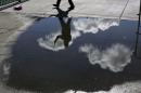 Pedestrian snaps a photograph while reflected in a rain puddle along The Embarcadero in San Francisco