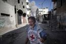 A International Red Cross employee runs for cover after an Israeli strike during a two-hour temporary ceasefire in Gaza City's Shijaiyah neighborhood, Wednesday, July 23, 2014. Israeli troops battled Hamas militants on Wednesday near a southern Gaza Strip town as U.S. Secretary of State John Kerry reported progress in efforts to broker a truce in a war that has so far killed more than 650 Palestinians and at least 30 Israelis. (AP Photo/Khalil Hamra)