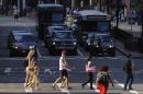 Pedestrians cross the street as cars wait at an intersection in Boston