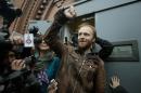 Russian freelance photographer Denis Sinyakov, center, rises his fist outside the gates of "Kresty" St. Petersburg prison, after he was released in St. Petersburg, Russia, Thursday, Nov. 21, 2013. Two more of the 30 people arrested by Russia following a Greenpeace protest in the Arctic two months ago have been freed on bail. Sinyakov and activist Andrei Allakhverdov walked out of a detention center on Thursday. The 30 were arrested in September after a Greenpeace ship, the Arctic Sunrise, entered Arctic waters despite Russian warnings. (AP Photo/Pavel Golovkin)