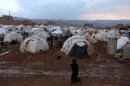CAPTION CORRECTION, CORRECTS SPELLING OF TOWN - A Syrian refuge woman walks past tents at a refugee camp in the eastern Lebanese border town of Arsal, Lebanon, Monday, Nov. 18, 2013. Thousands of Syrians have fled to Lebanon over the past days as government forces attack the western town of Qara near the border with Lebanon. (AP Photo/Bilal Hussein)