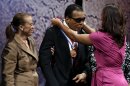 Retired boxing champion Muhammad Ali, center, receives the Liberty Medal from his daughter Laila Ali with his wife Lonnie Ali at his left during a ceremony at the National Constitution Center, Thursday, Sept. 13, 2012, in Philadelphia. The honor is given annually to an individual who displays courage and conviction while striving to secure liberty for people worldwide. (AP Photo/Matt Rourke)