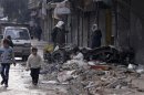 Boys walk past a car damaged by shelling in the al-Mashhad district of Aleppo