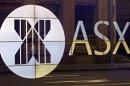 An office worker walks past the board of the Australian Securities Exchange building displaying its logo in central Sydney