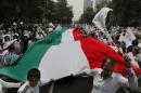 Demonstrators walk with a giant Mexican national flag during a march organized by representatives of the National Front for the Family, in Mexico City, Saturday, Sept. 24, 2016. Dueling marches, in support and against Mexican President Enrique Pena Nieto's push to legalize same-sex marriage, gathered at the Angel of Independence monument. The two sides were kept apart Saturday by hundreds of police and barriers erected around the city's iconic monument. (AP Photo/Marco Ugarte