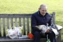 An elderly man feeds pigeons in St James's Park in London