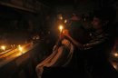 A customer holds a candle as he gets his haircut at a barber's shop during a power-cut in Kolkata