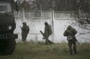 Uniformed men believed to be Russian servicemen walk around a Ukrainian military base near Sevastopol