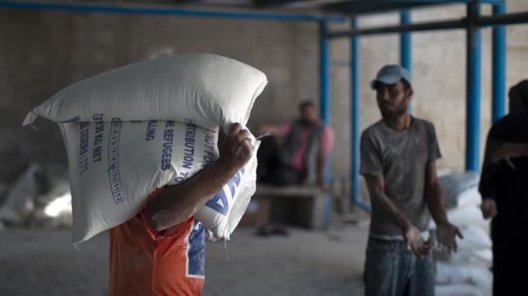 A Palestinian man carries bags of wheat flour distributed at an aid distribution centre of the United Nations Relief and Works Agency (UNRWA) in Gaza City on September 17, 2013