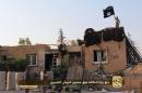 A Jihadist media outlet Welayat Raqa image from July 25, 2014, allegedly shows Islamic state militants raising their black and white flag over a building belonging to a Syrian army base in the northern rebel-held city of Raqa