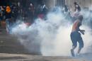 Anti-government protesters run from tear gas during a protest against Maduro's government in Caracas