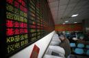 Investors look at computer screens showing stock information at a brokerage house in Shanghai