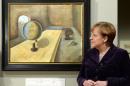German chancellor Angela Merkel poses by a painting "The Refugee" by Felix Nussbaum on January 25, 2016 in Berlin during the opening of the exhibition "Art from the Holocaust -100 Works from the Yad Vashem Collection" at the History museum in Berlin
