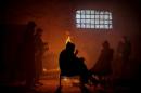 FILE PHOTO: Migrants warm themselves by the fire inside a derelict customs warehouse in Belgrade