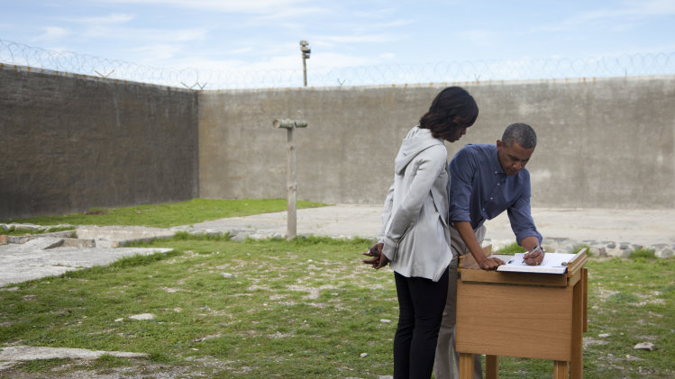U.S. President Barack Obama, right, and first lady Michelle Obama sign a guest book during a tour of Robben Island on Sunday, June 30, 2013, in Robben Island, South Africa. Robben Island is a historic Apartheid-era prison that held black political prisoners including former South African president and anti-apartheid hero Nelson Mandela. (AP Photo/Evan Vucci)