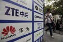 Man walks past an advertisement board showing the logos of Huawei and ZTE on it, outside a mobile phone repair shop in Wuhan