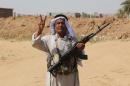 An Iraqi Sunni gunman, who took up arms alongside security forces to defend the town of Dhuluiyah from jihadists, flashes the V-sign as he holds a position in the Jubur area on September 17, 2014