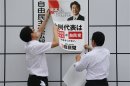 Staff members of Japan's ruling Liberal Democratic Party post an election poster with the image of Japan's PM Abe in Tokyo