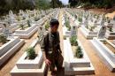 A member of the PKK walks past graves at a cemetary on July 29, 2015 deep in the Qandil mountain, the PKK headquarters in northern Iraq