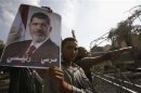 A member of Muslim Brotherhood and supporter of President Mursi holds up poster of Mursi behind barbed wires outside Republican Guard headquarters in Cairo