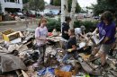 Katie Byrne, left, her neighbor Elizabeth Dipert, center, and church volunteer Linda Pekarek, right, sift through thrown out rotting flood refuse looking for valuables, at Byrne's home in Longmont, Colo., Wednesday Sept. 18, 2013. Statewide, only about 22,000 homeowners have flood insurance policies, FEMA spokesman Jerry DeFelice said. With 2.2 million housing units in Colorado, according to Census figures, that means about 1 percent of the state's residences have flood coverage. (AP Photo/Brennan Linsley)