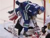 Vancouver Canucks' Zack Kassian steps over Chicago Blackhawks' goaltender Corey Crawford during the second period of their NHL hockey game in Vancouver