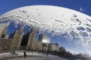 A woman and the Chicago skyline are reflected in the snow covered, curved surface of the "Cloud Gate" sculpture in Chicago