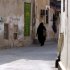 A Bahraini woman walks down a narrow street in the western Shiite village of Malkiya, Bahrain, on Tuesday, Nov. 22, 2011, painted and repainted with anti-government graffiti and hung with religious banners for the Islamic month of Muharram, a time of Shiite mourning for Imam Hussein, grandson of Islam's founding prophet Mohamed. (AP Photo/Hasan Jamali)