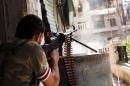 A rebel fighter fires his gun against a Syrian government troop position in Aleppo, on October 21, 2012